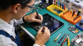 Technician focused on repairing a tablet in a well-lit workspace, highlighting expertise in device repair